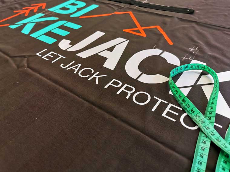 Schwarzer Stoff mit BIKEJACK Logo und türkisem Maßband